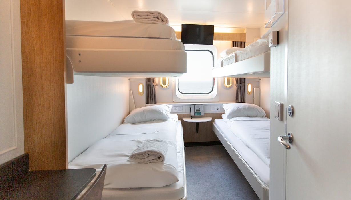 Kahyt med køjesenge, vindue og bord under.