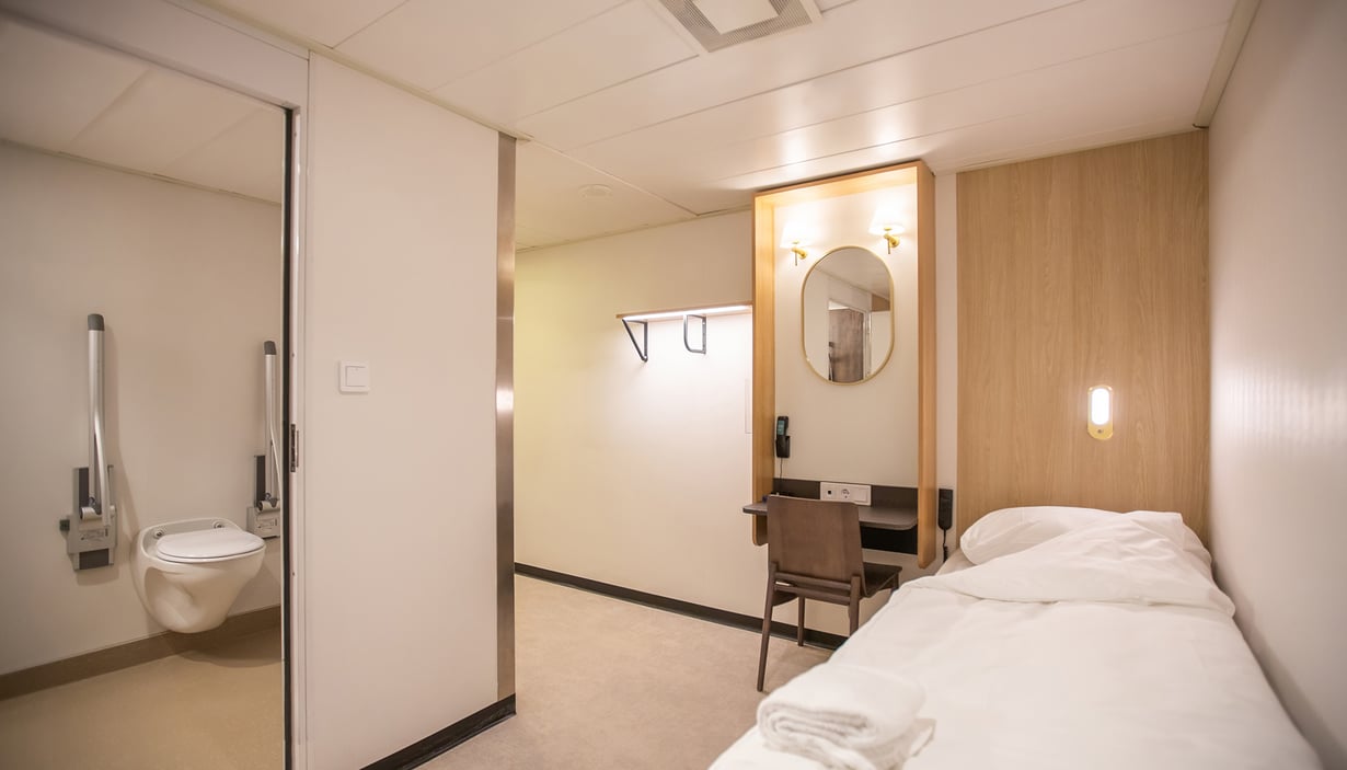 Handicapvenlig kahyt med seng, skrivebord og badeværelse.