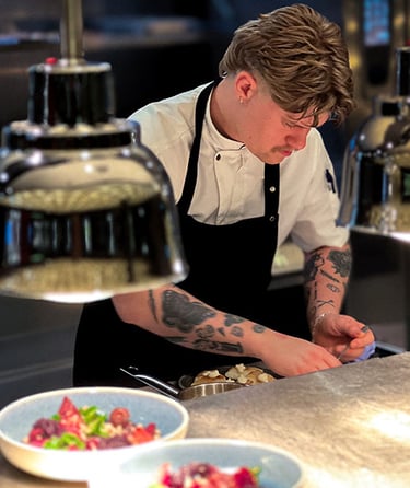 En kok der tilbereder mad i et professionelt køkken.