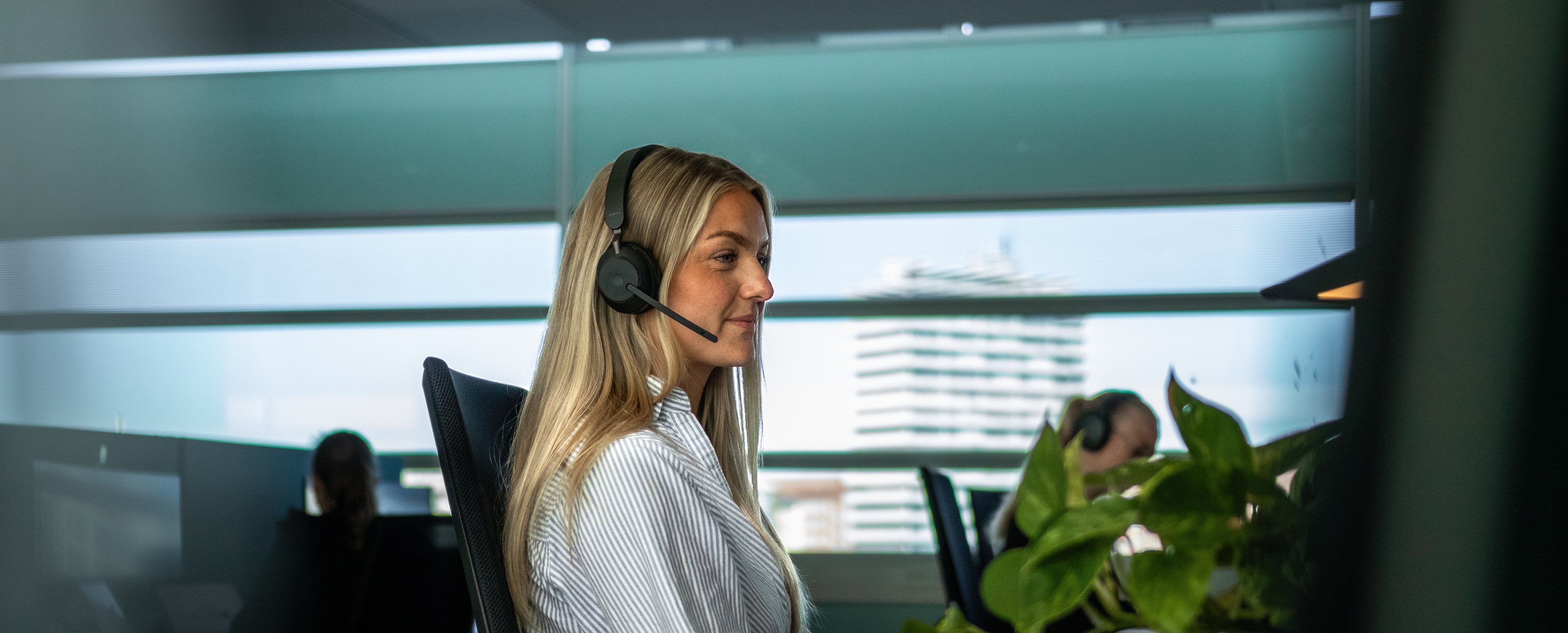 Person arbejder ved skrivebord med computer og hovedtelefoner