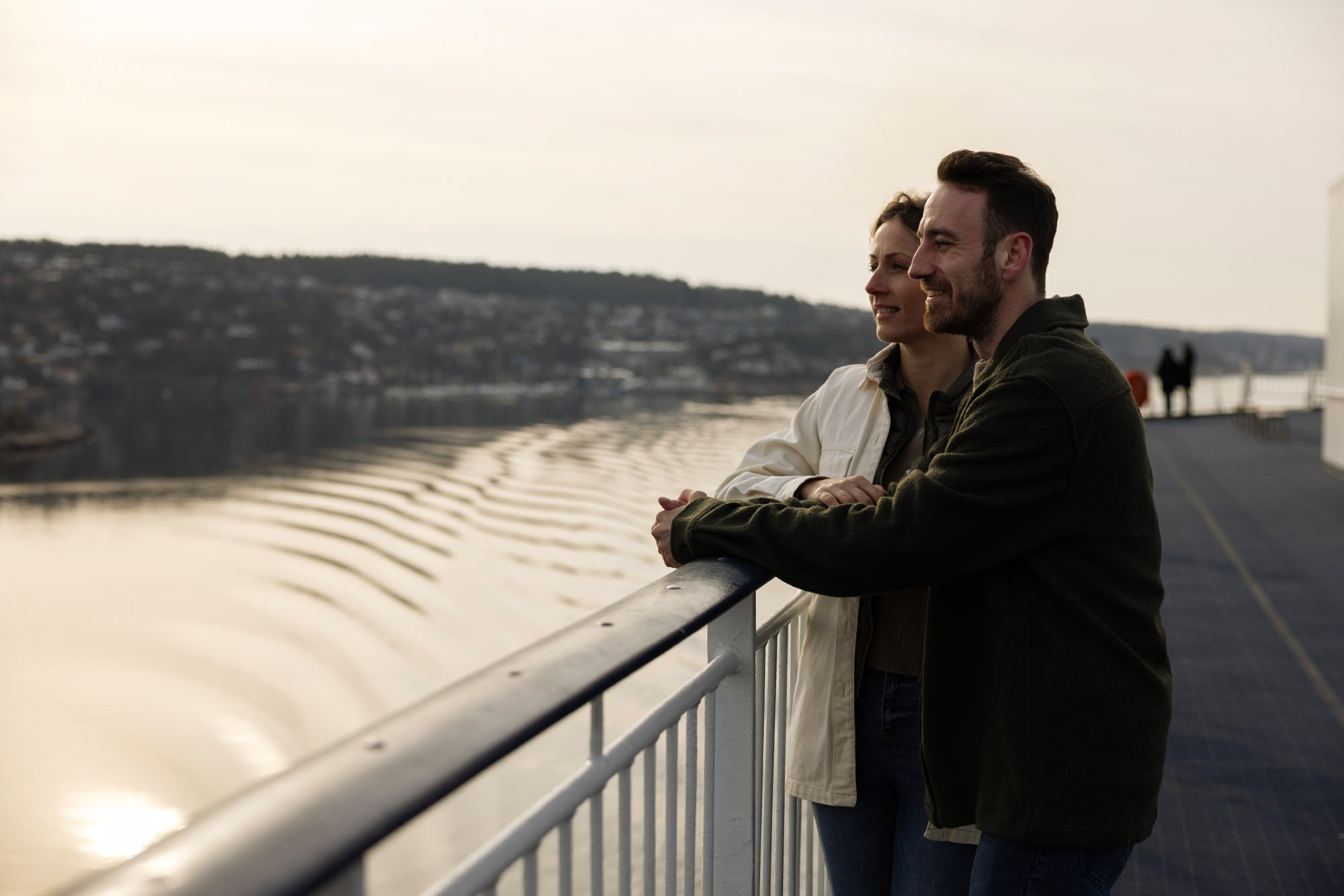 To personer står på et dæk og kigger ud over en vandmasse.