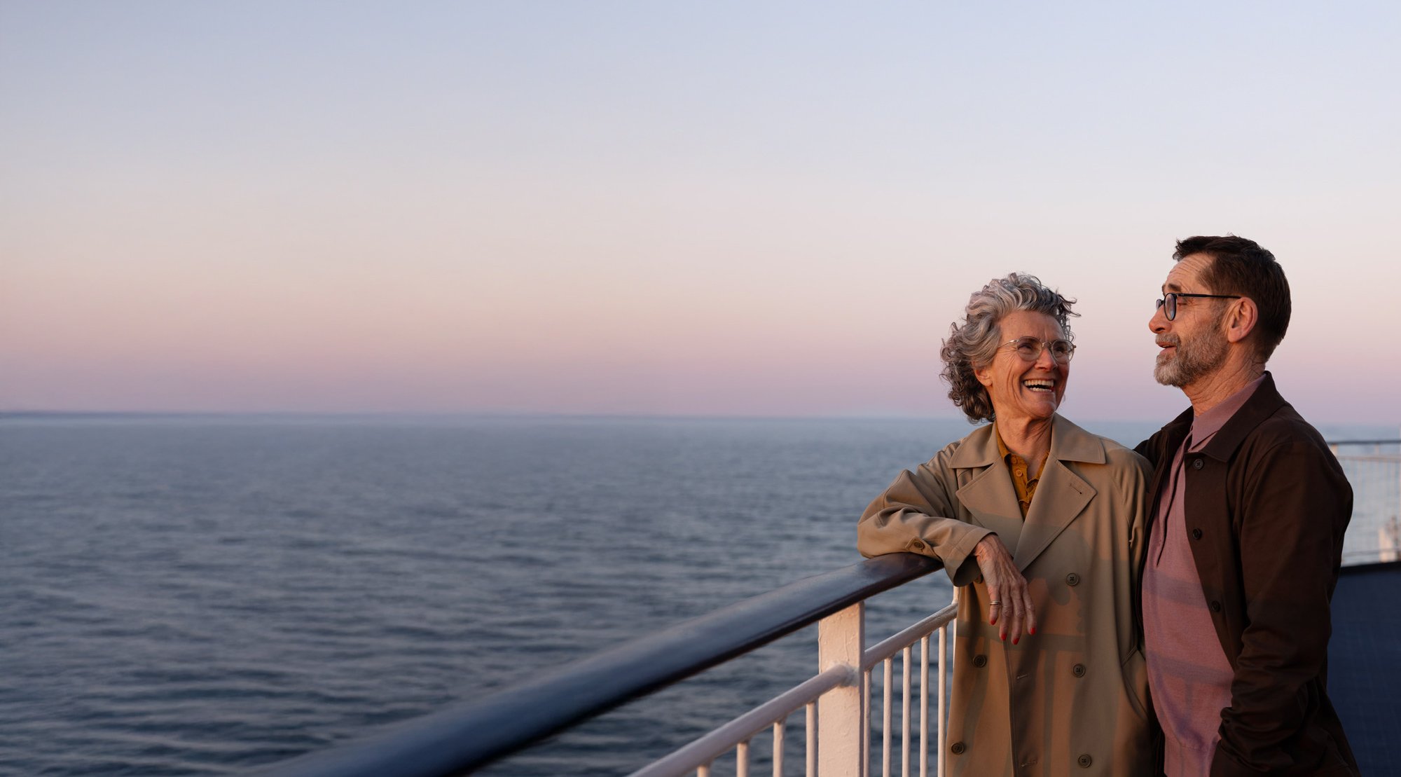 To personer står på dækket af et skib og kigger ud over havet.