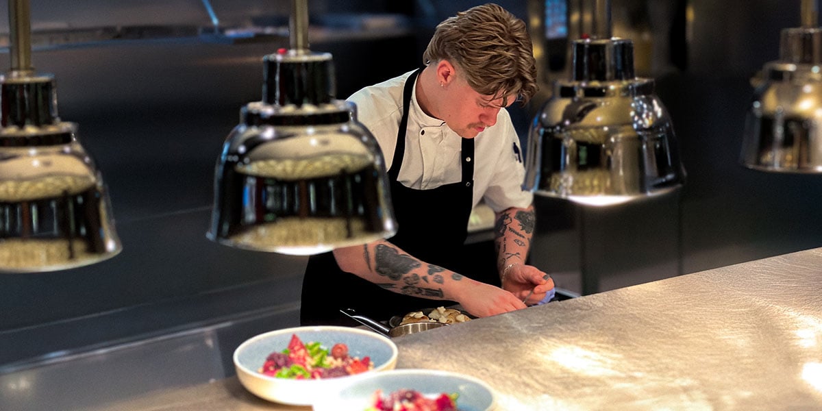 En kok der tilbereder mad i et professionelt køkken.