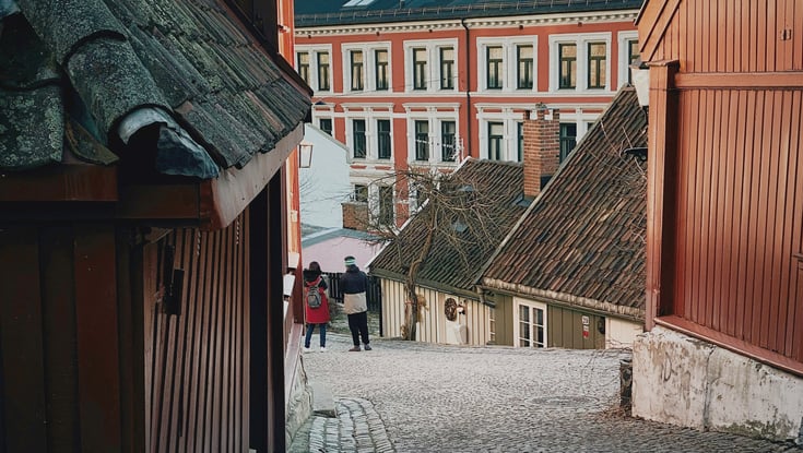 Smal brostensbelagt gade med traditionelle træhuse i Oslo.