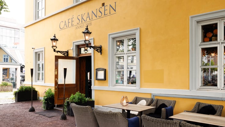 Café Skansens facade med udendørs servering i Oslo.