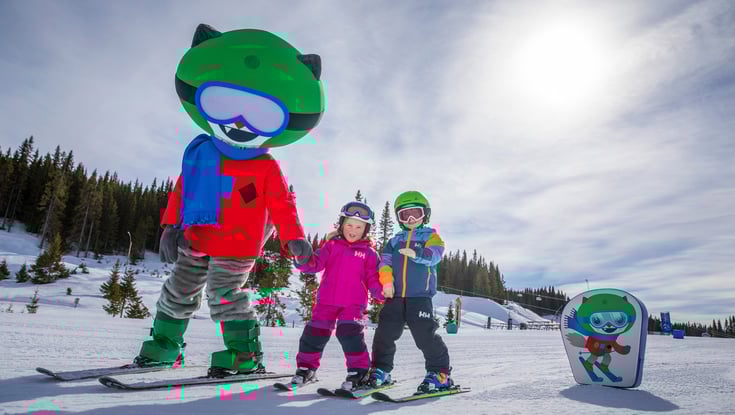 Maskot står på ski med børn i Hafjell skiområde