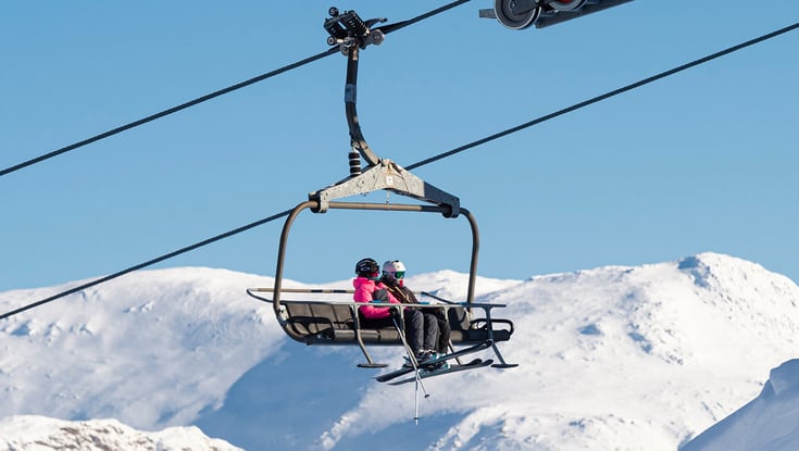 Skilift med to personer på et snedækket bjerg.