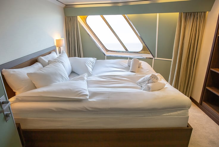  Kahyt med pænt redt seng, vindue og håndklædesvaner.