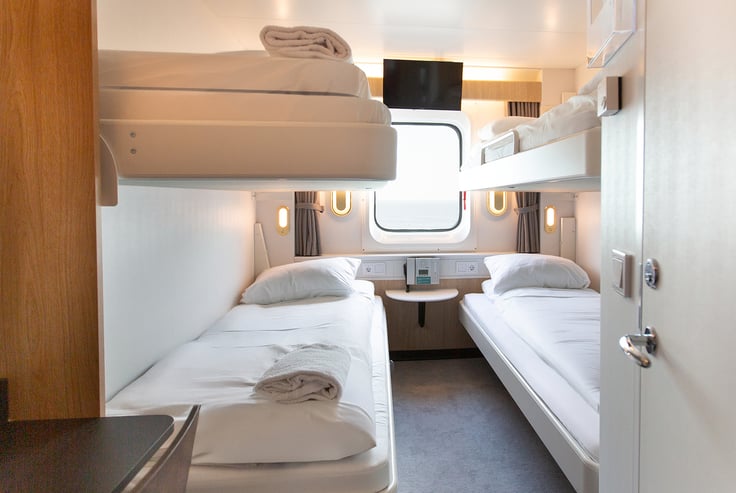 Kahyt med køjesenge, vindue og bord under.