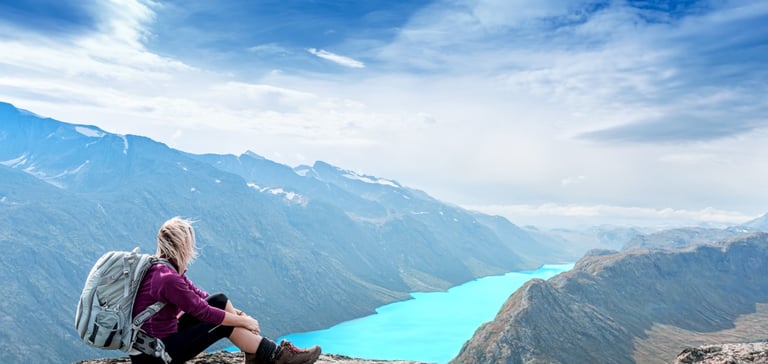 Person på klippe med udsigt over landskab med bjerge i Norge 