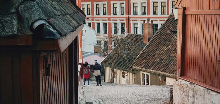 Smal brostensbelagt gade med traditionelle træhuse i Oslo.