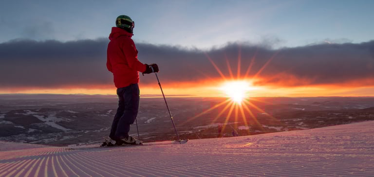 Person med skistave på en sneklædt bakke i Trysil ved solnedgang.