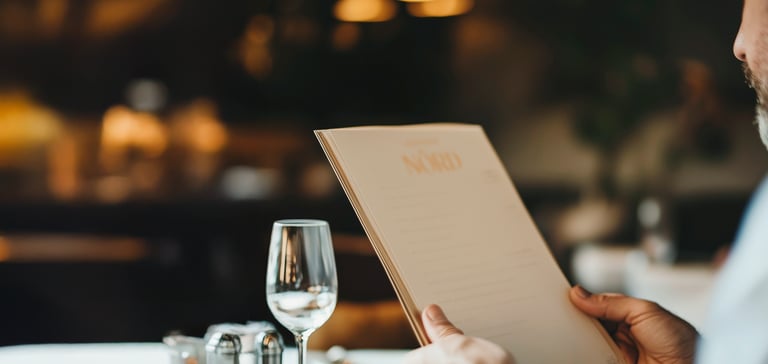 Person holder menu på NÓRD restaurant.
