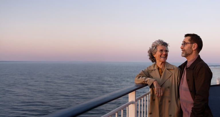 To personer står på dækket af et skib og kigger ud over havet.