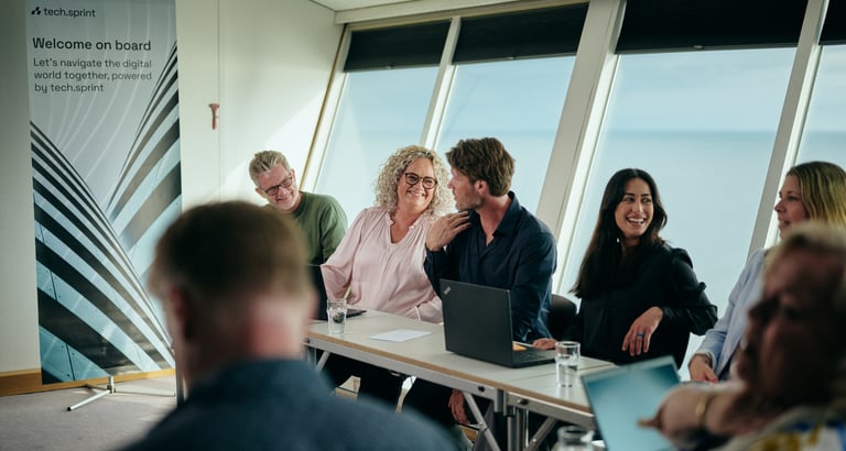 Møde med laptops ved vandudsigt, banner: "Welcome on board..."