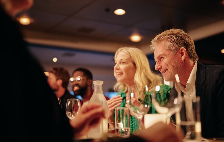 Venner samlet rundt om et restaurantbord med vin og vand, nyder en hyggelig aften indendørs