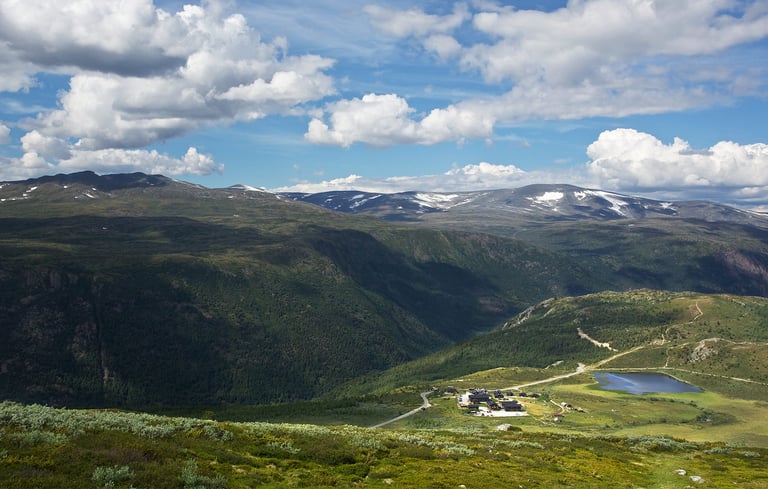 Bjergdal ved Lillehammer med små bygninger og en sø.