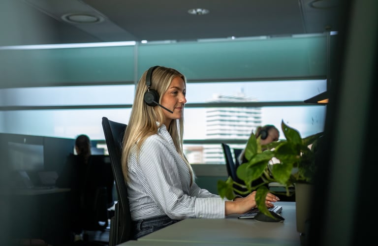 Person arbejder ved skrivebord med computer og hovedtelefoner