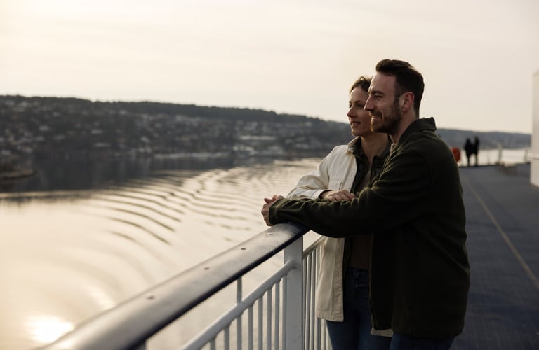 To personer står på et dæk og kigger ud over en vandmasse.