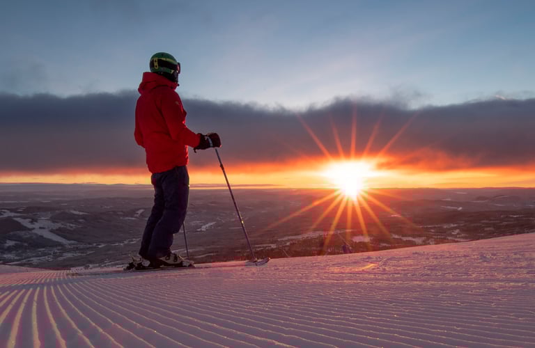Person med skistave på en sneklædt bakke i Trysil ved solnedgang.