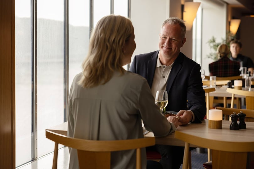 To personer sidder ved et bord i en restaurant og holder hænder.